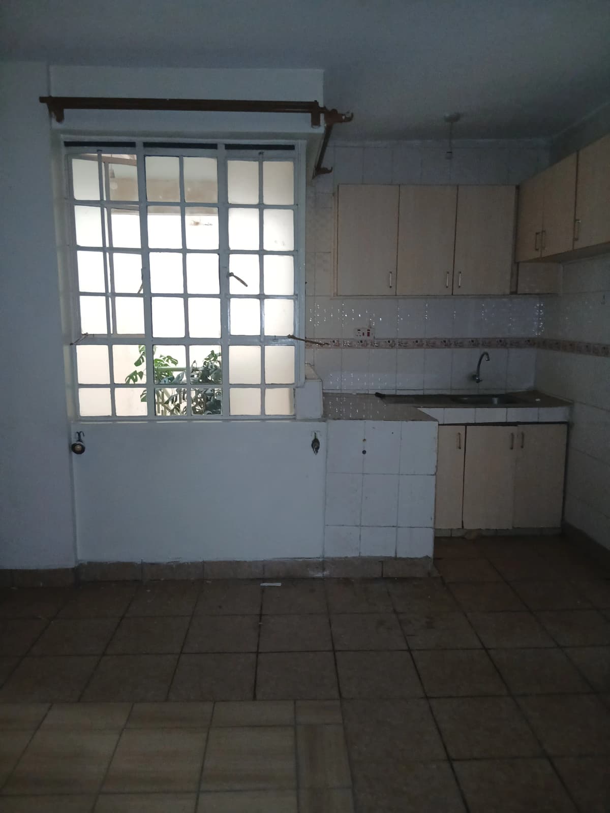 Compact kitchen with white cabinetry and barred window