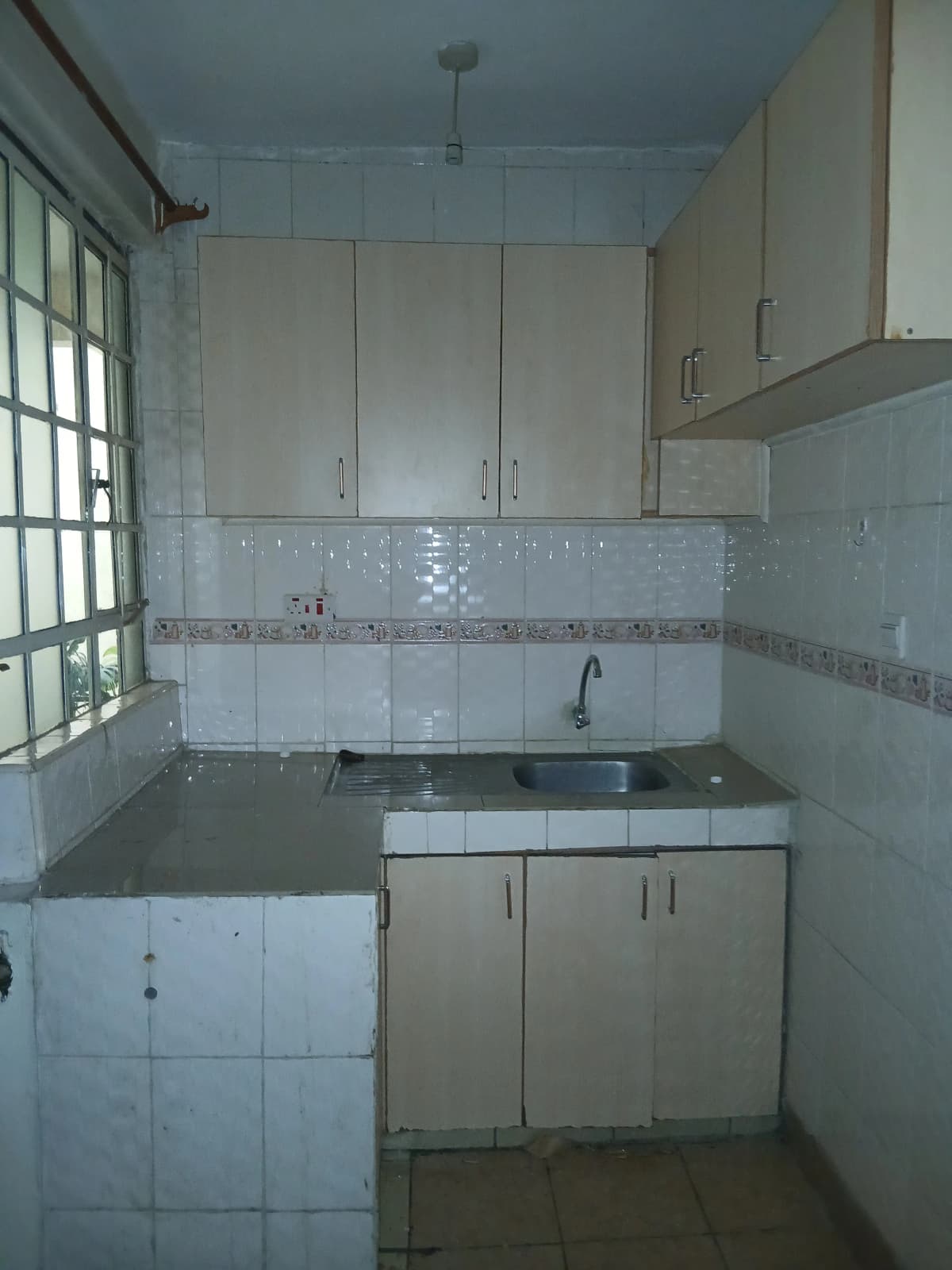 Compact kitchen with white cabinetry, tiled backsplash, small window