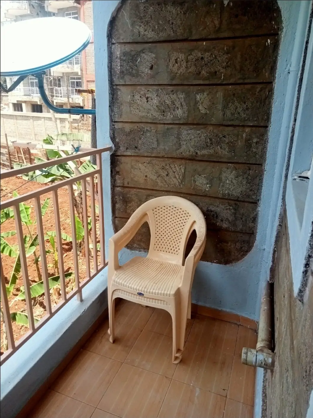 Small balcony with plastic chair and metal railing