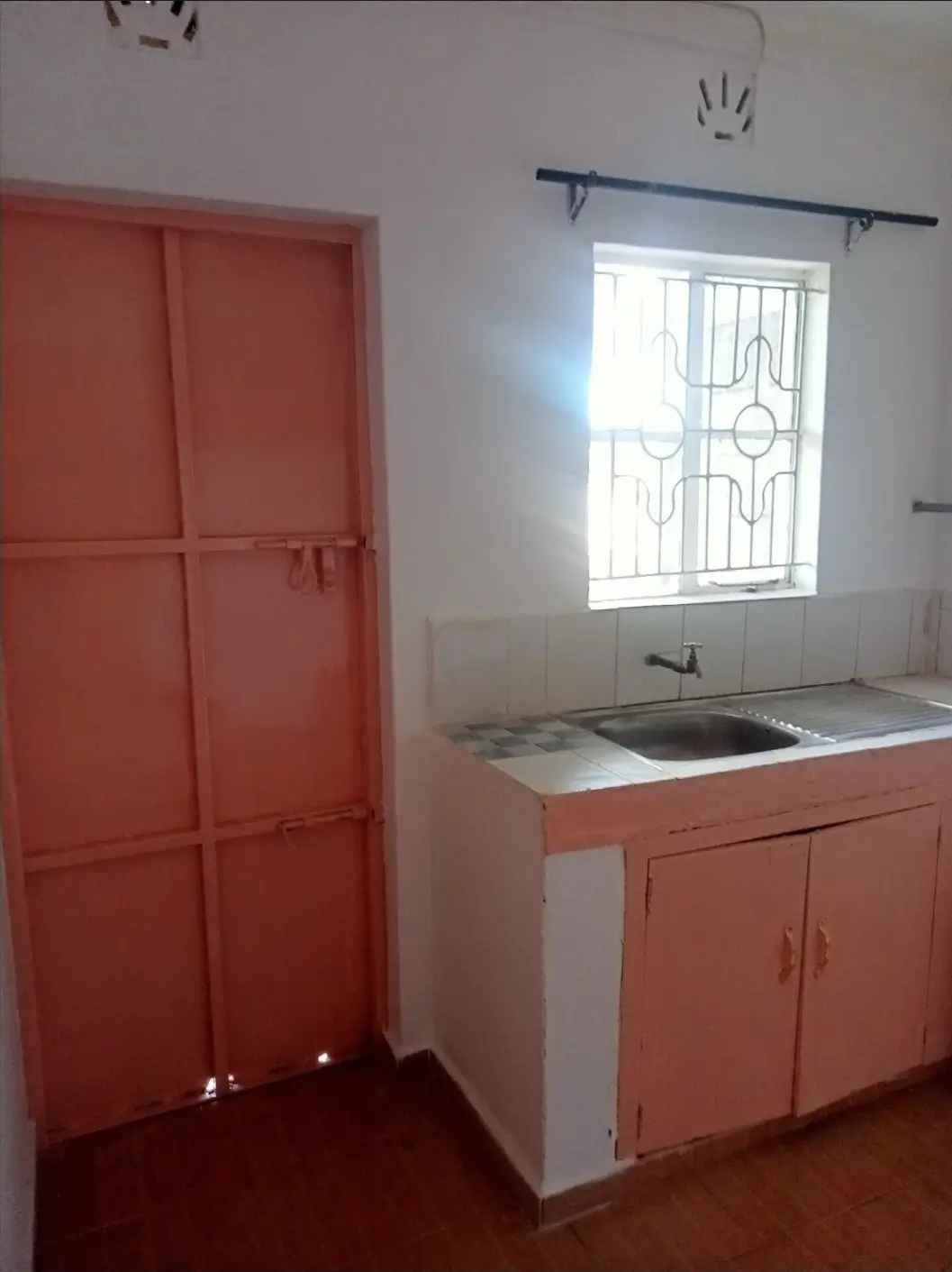 Compact kitchen with orange cabinetry and single sink basin
