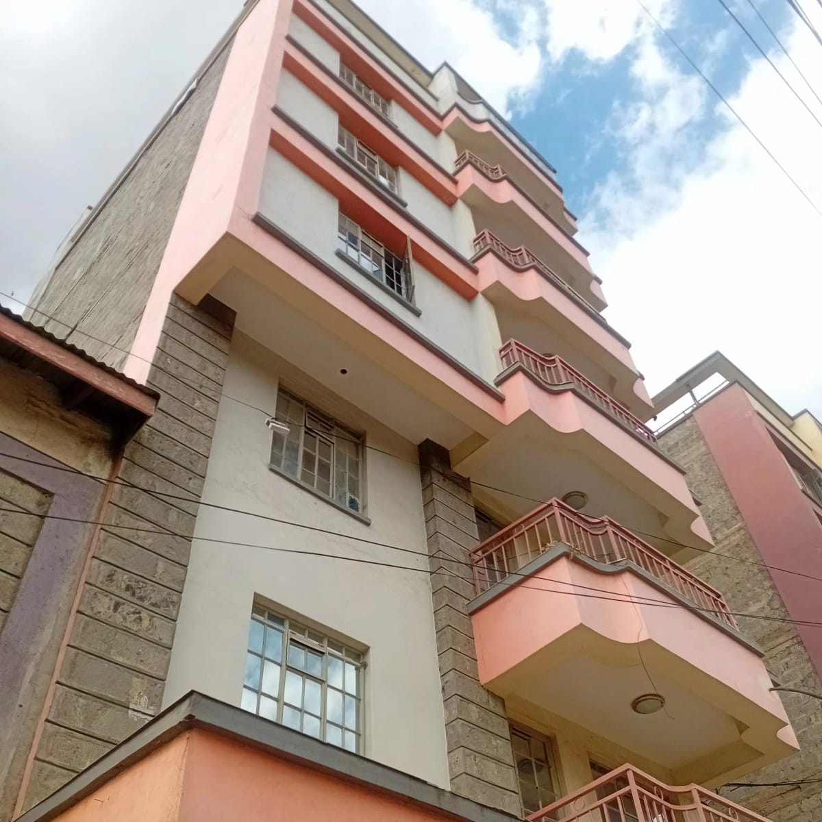 Multi-story residential building with pink and white facade, balconies