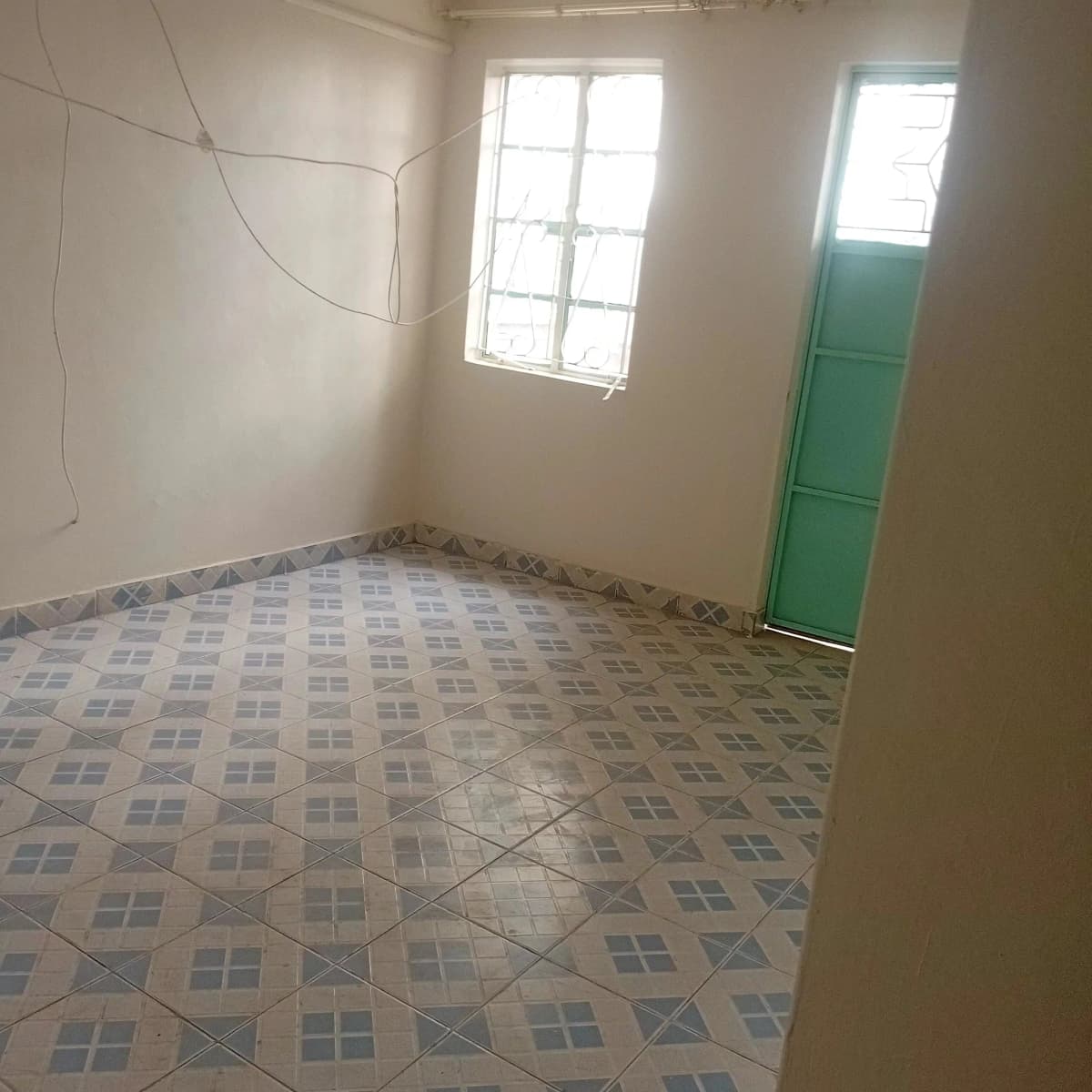 Empty bedroom with patterned tile floor and window
