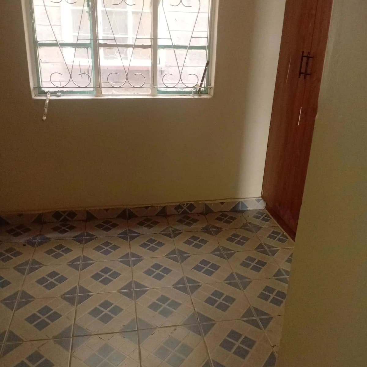 Empty bedroom with geometric tile flooring and barred window