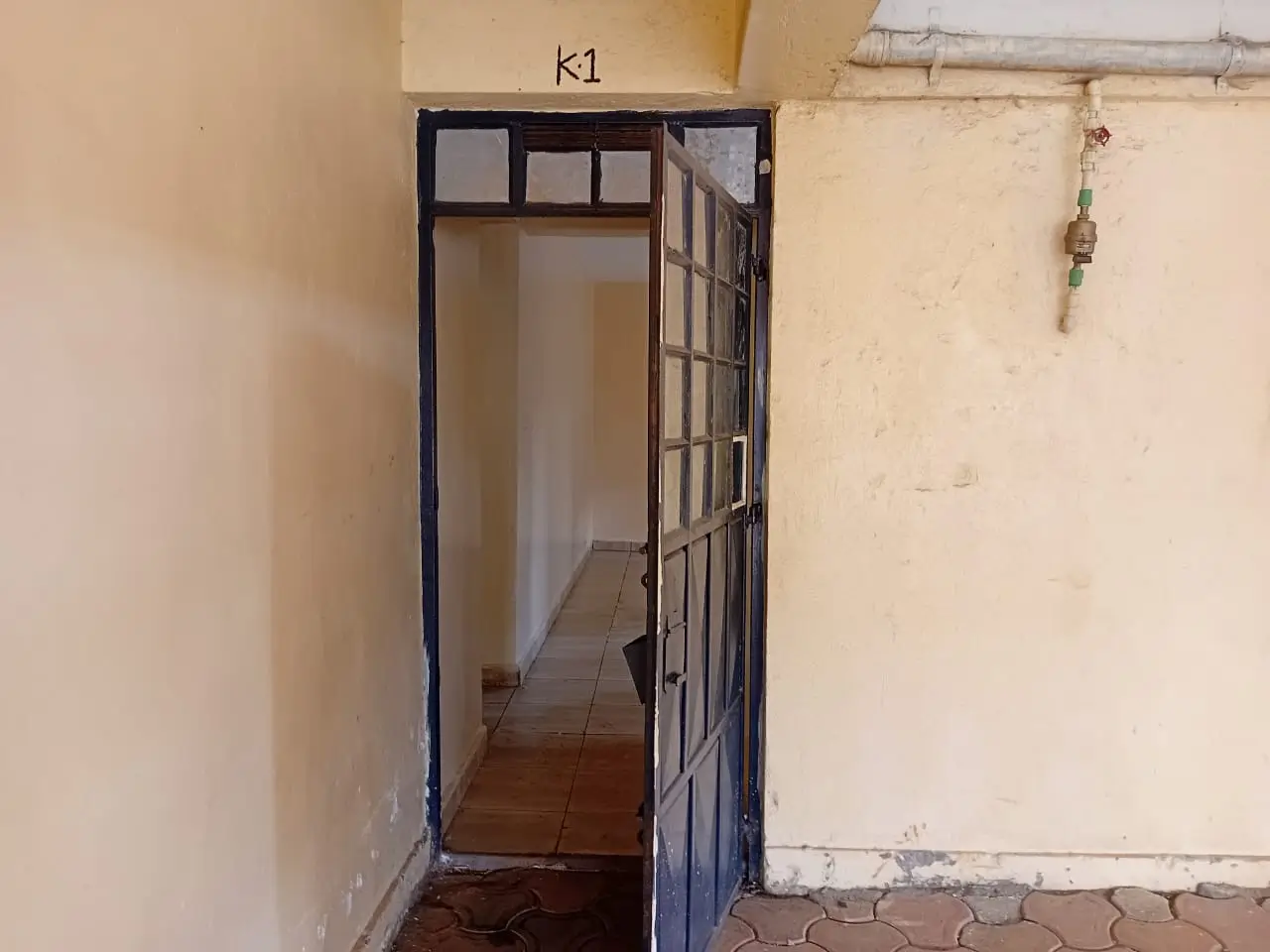 Narrow corridor with black-framed doorway and terracotta flooring