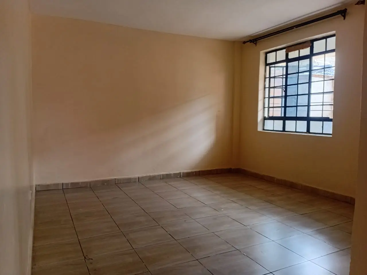 Spacious bedroom with tiled flooring and natural light