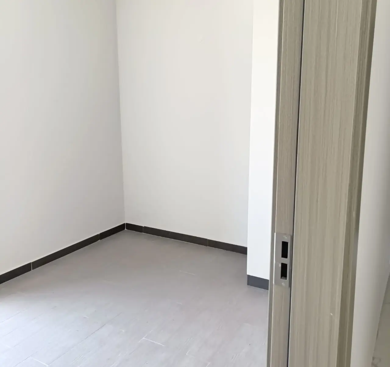 Empty bedroom with light wood door and black trim