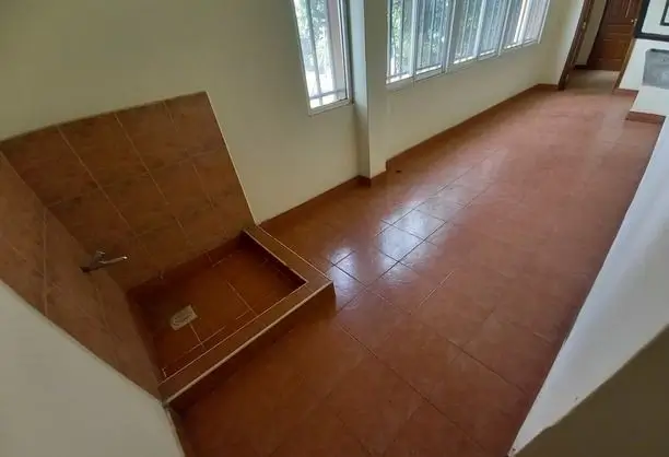 Empty bedroom with terracotta tile flooring and natural light