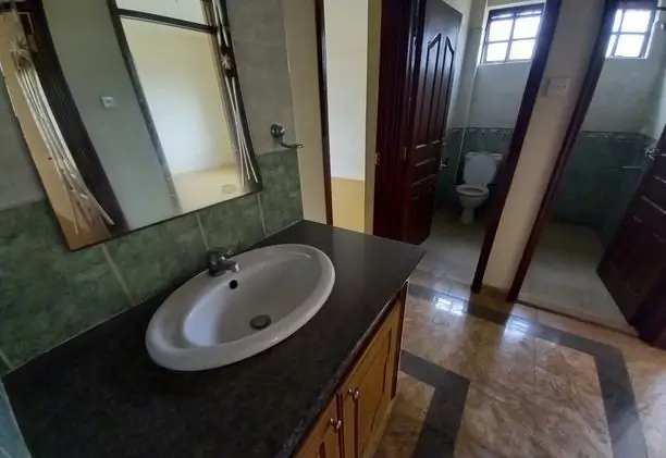 Spacious bathroom with round sink and green tile accents