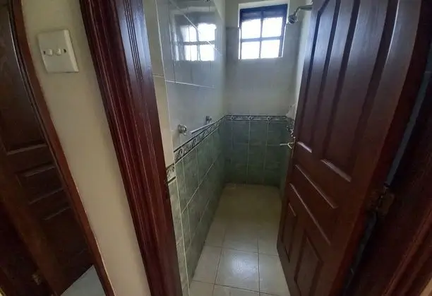 Narrow bathroom with tiled walls and small window