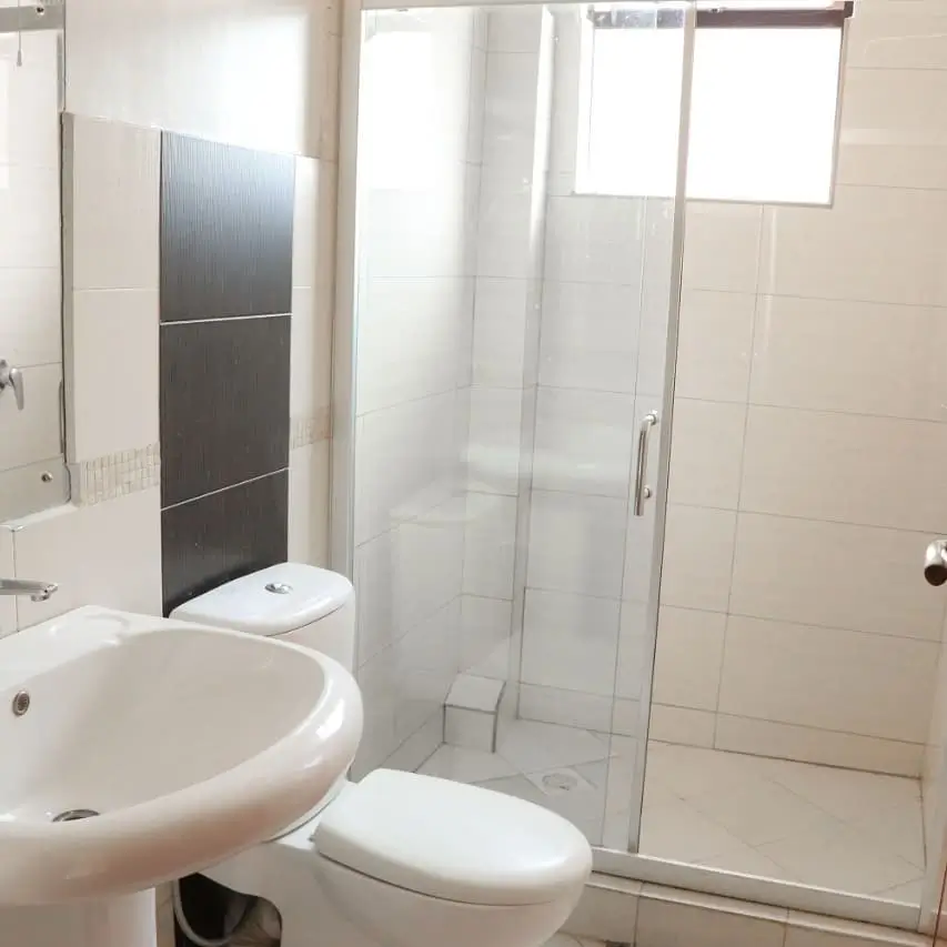 Modern bathroom with round sink, toilet, and glass shower enclosure