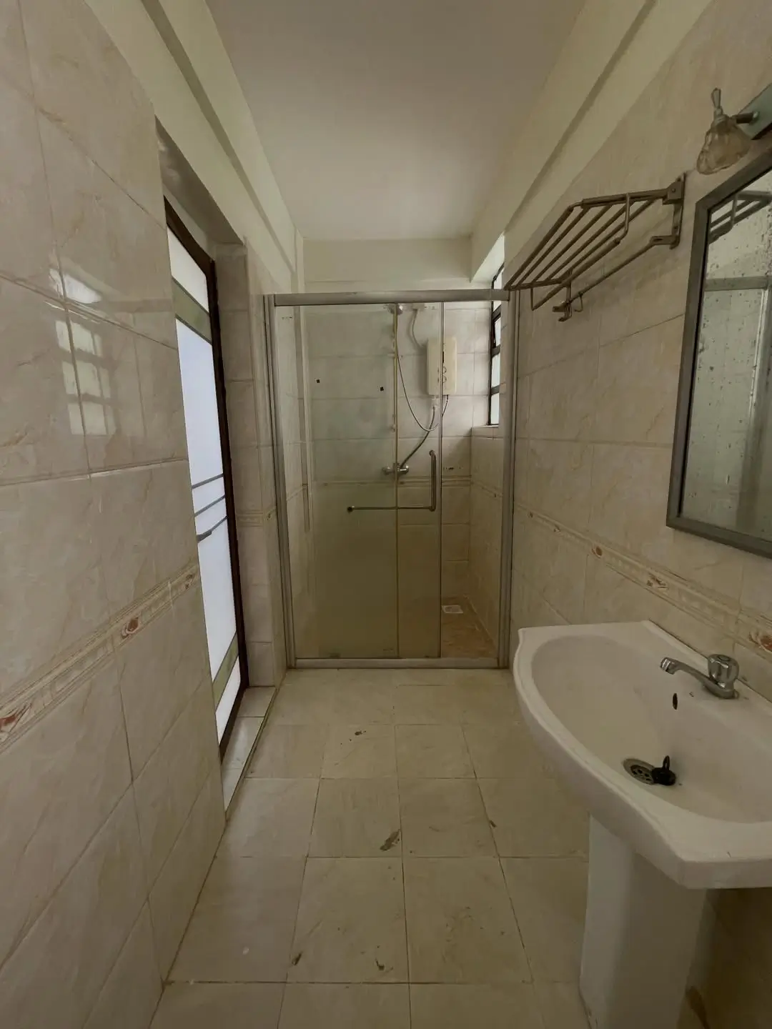 Bathroom with shower enclosure, pedestal sink, tile walls