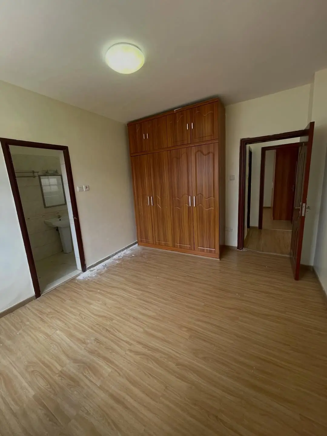 Spacious bedroom with wooden wardrobe and tiled flooring