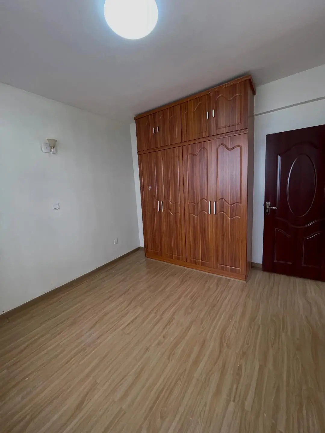 Empty bedroom with wooden wardrobes and laminate flooring