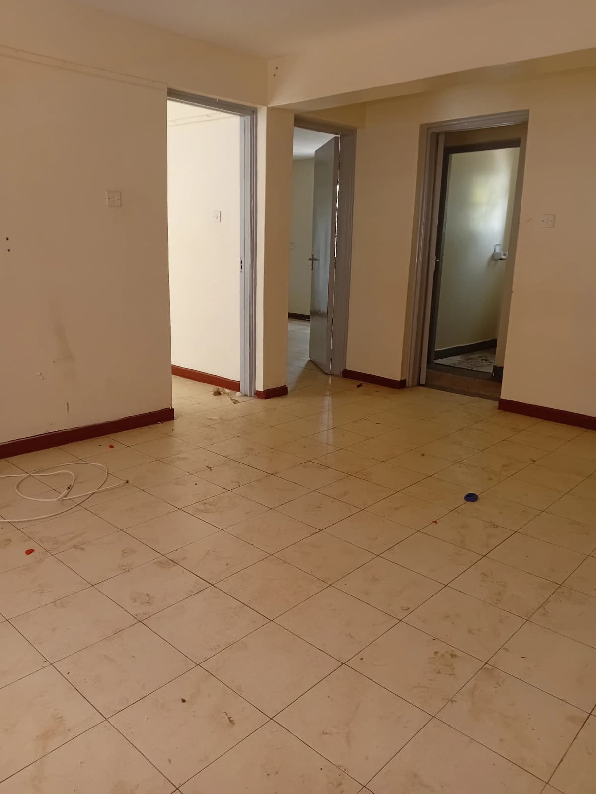 Empty living room with tile flooring and multiple doorways