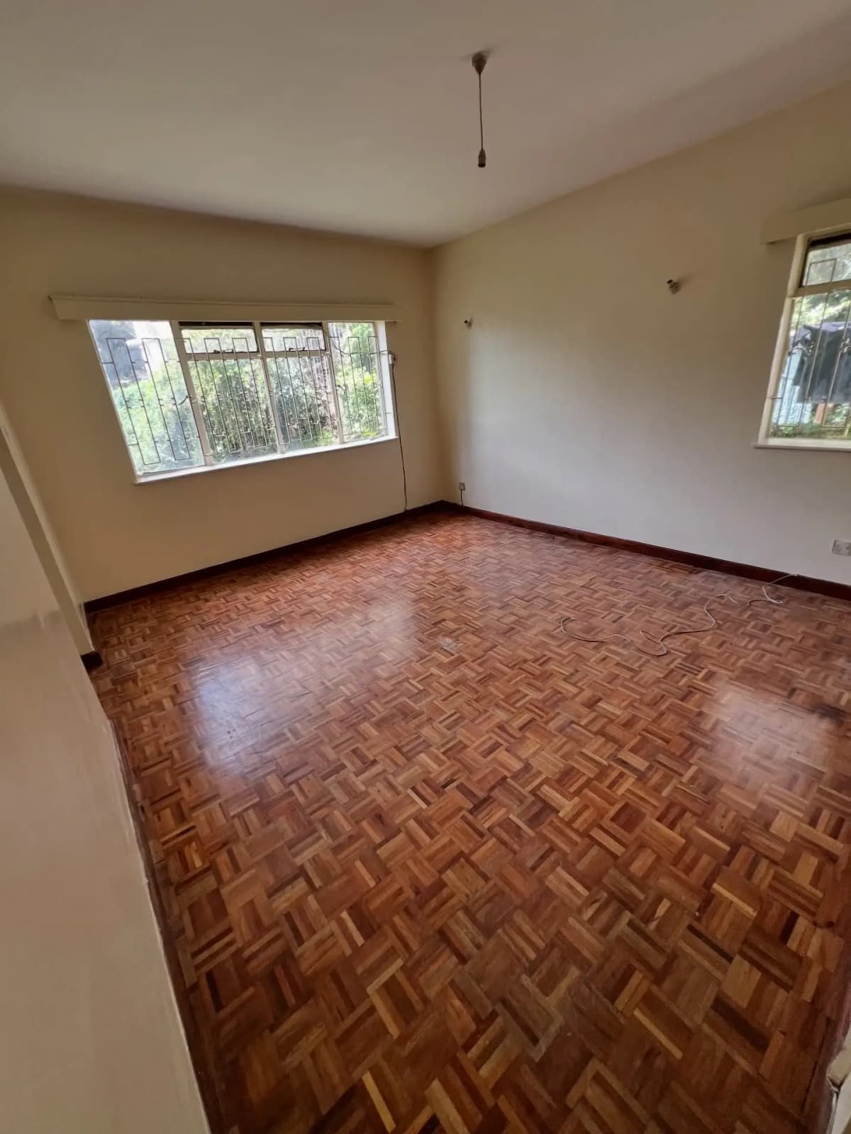 Empty living room with herringbone wooden flooring and windows