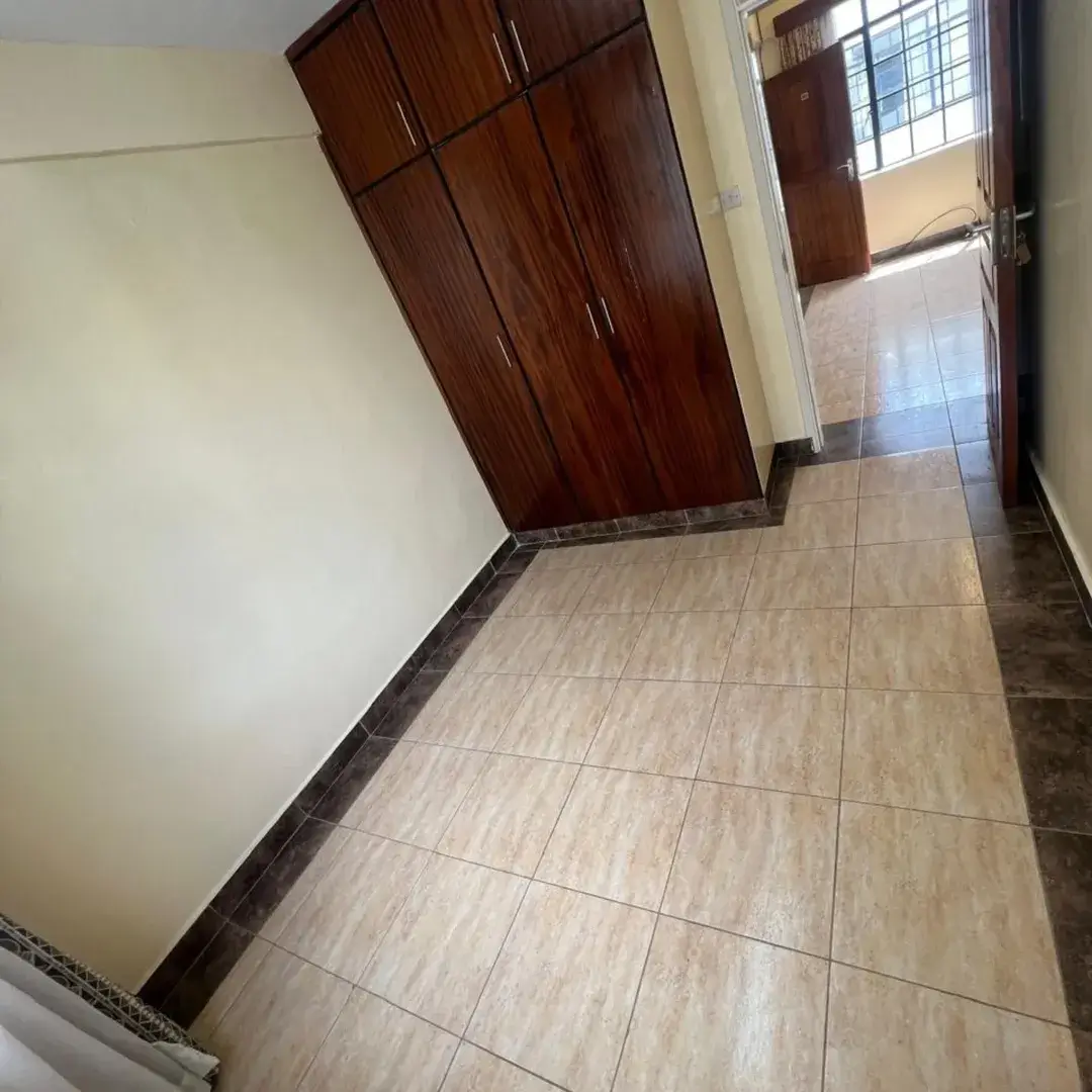 Spacious bedroom with wooden wardrobe and tiled flooring