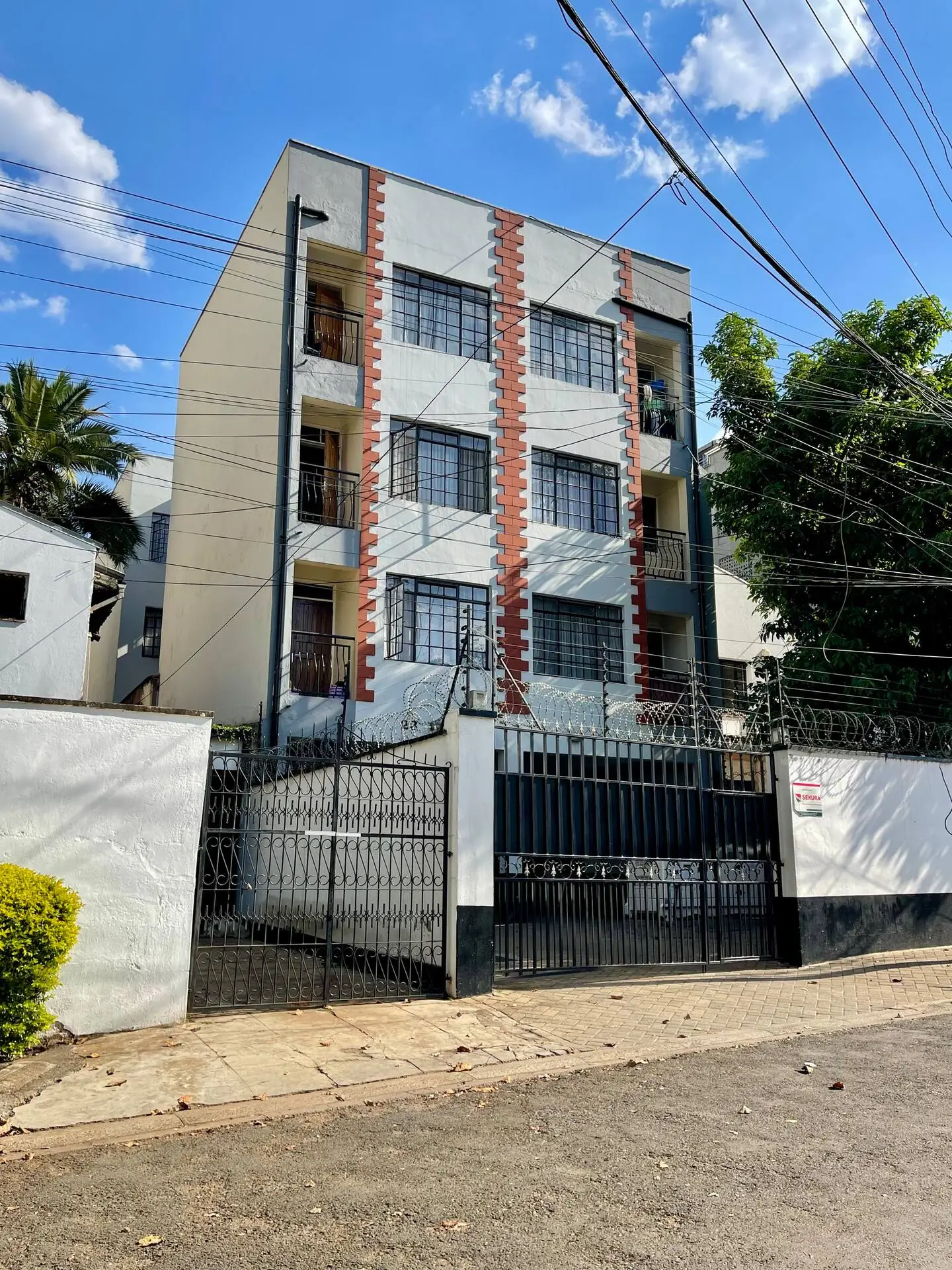 Three-story apartment building with brick columns and metal gate