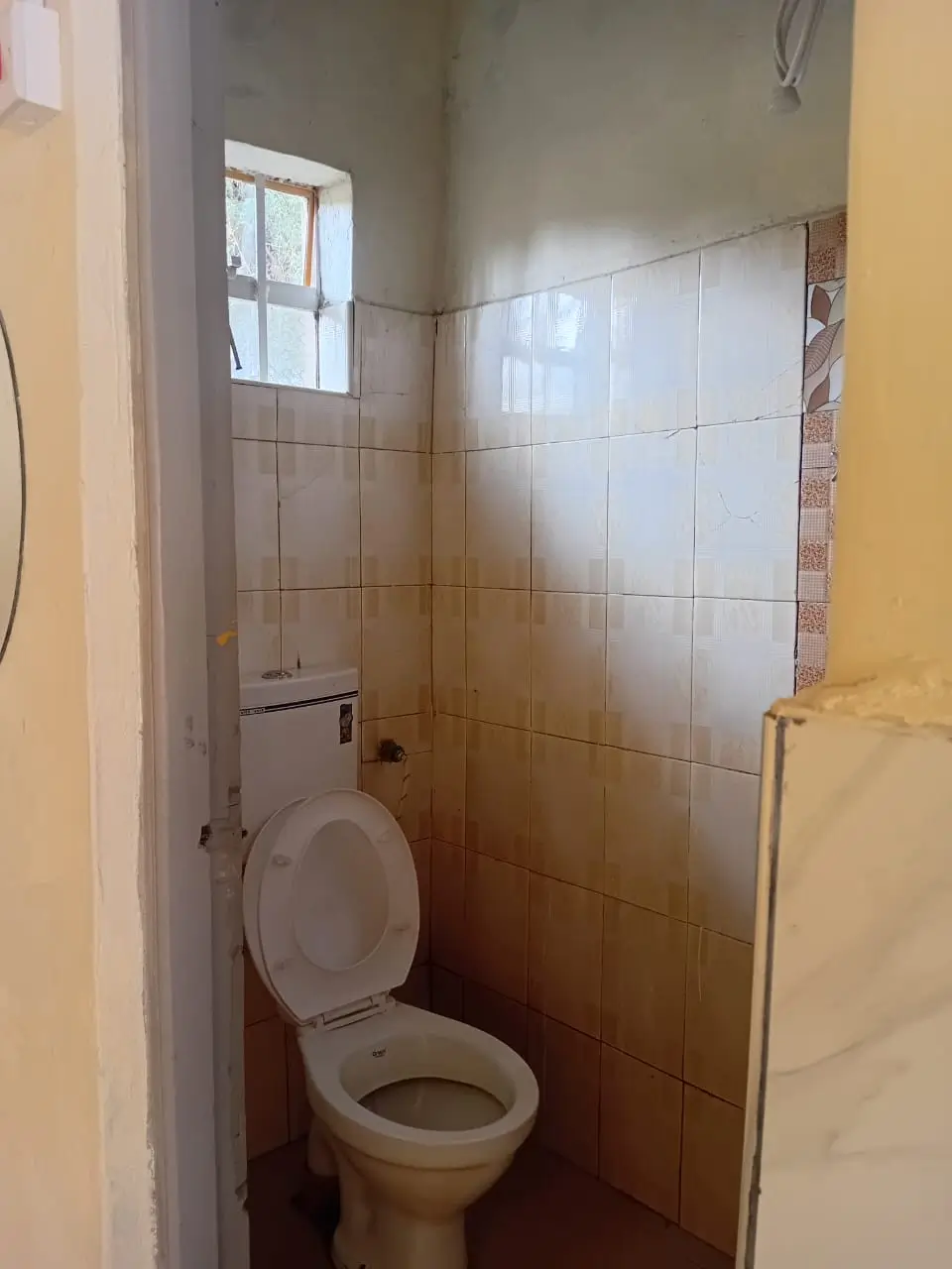 Compact bathroom with toilet, sink, and tiled shower enclosure