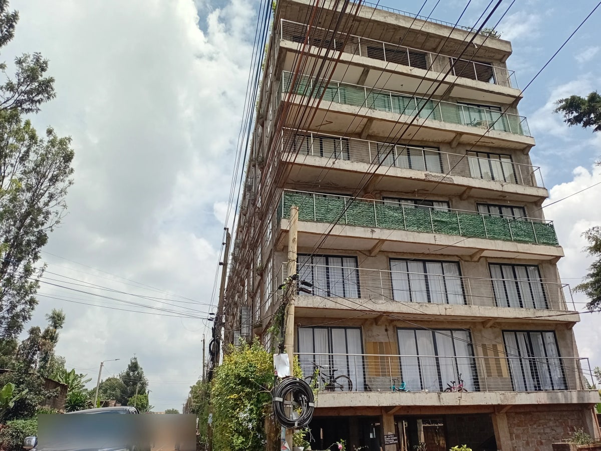 Multi-story residential building facade with balconies and ground-level parking