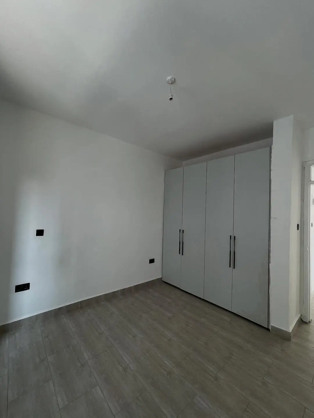 Empty bedroom with built-in wardrobes and wooden flooring