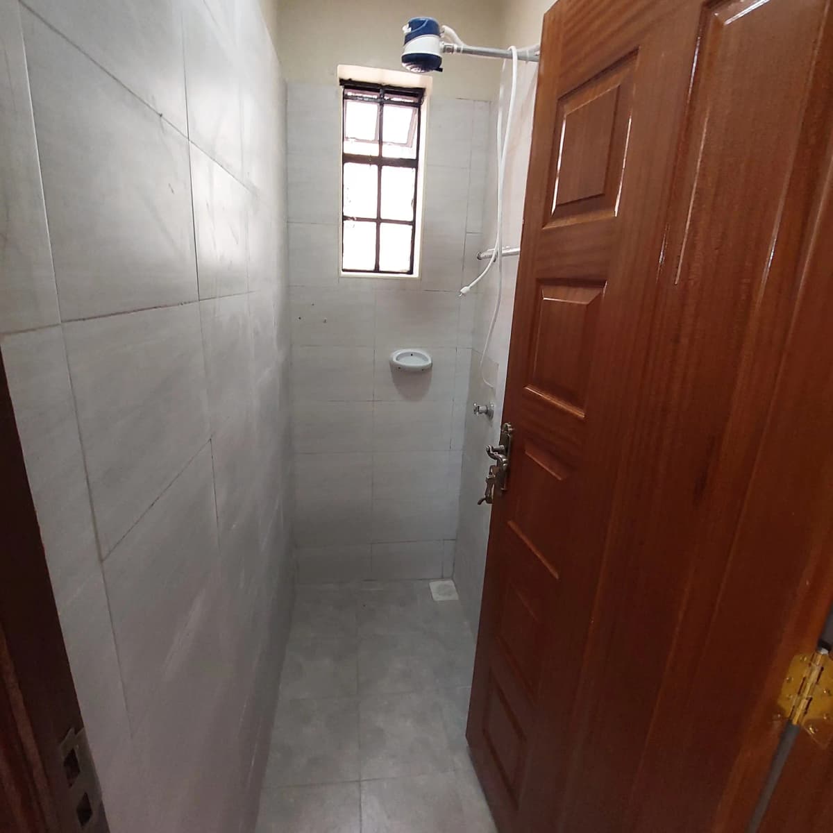 Narrow shower room with white tile walls and window
