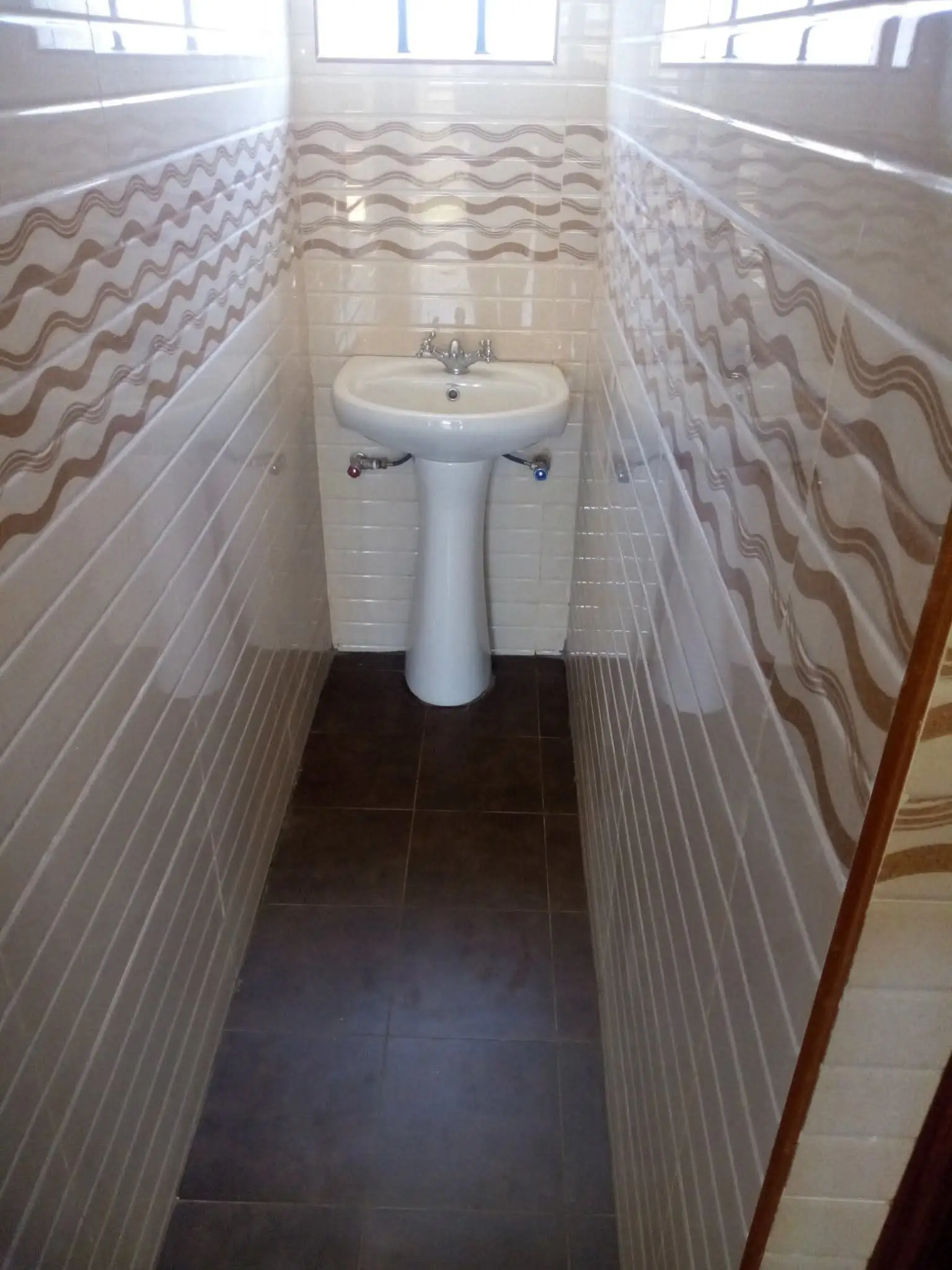 Narrow bathroom with pedestal sink and geometric tile walls