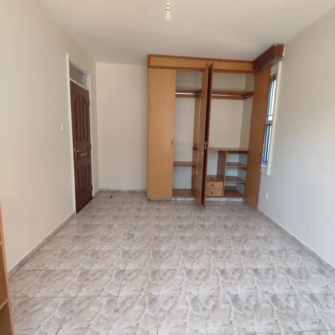 Spacious bedroom with built-in wooden wardrobe and tiled floor