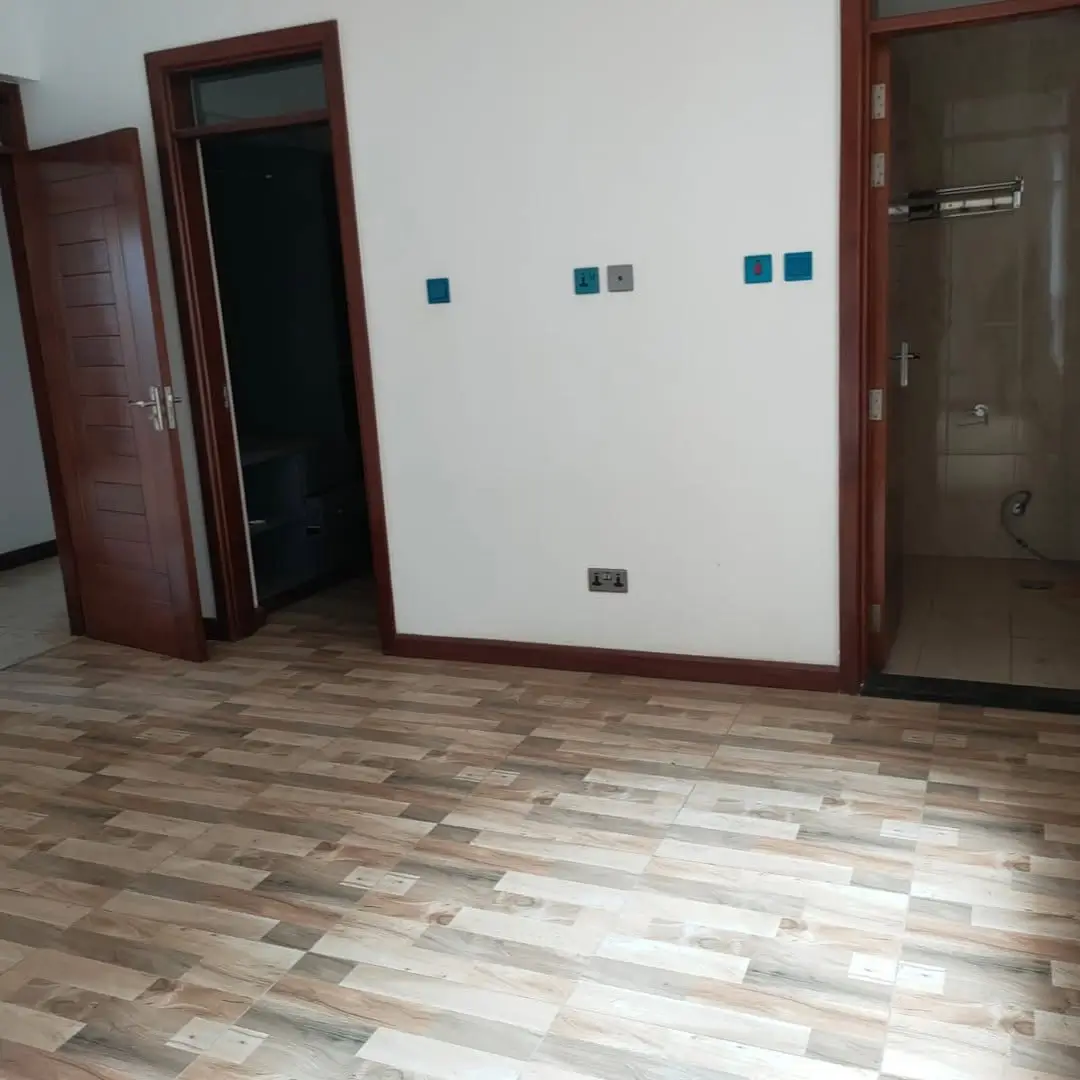 Empty bedroom with wooden flooring and multiple door access points