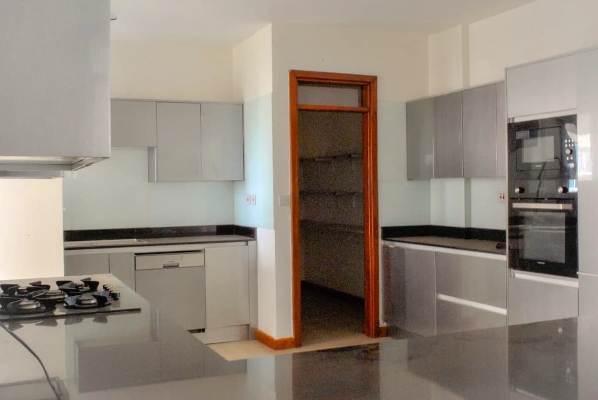 Modern kitchen with gas cooktop, built-in appliances, wood-framed pantry door