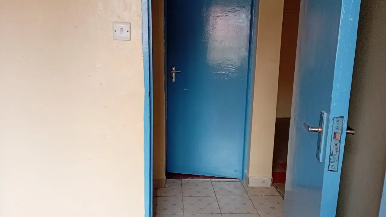 Corridor with blue door and tiled flooring