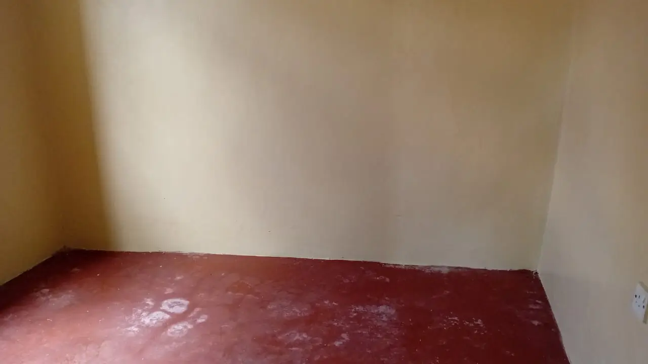 Bare bedroom with red-tiled floor and plain walls