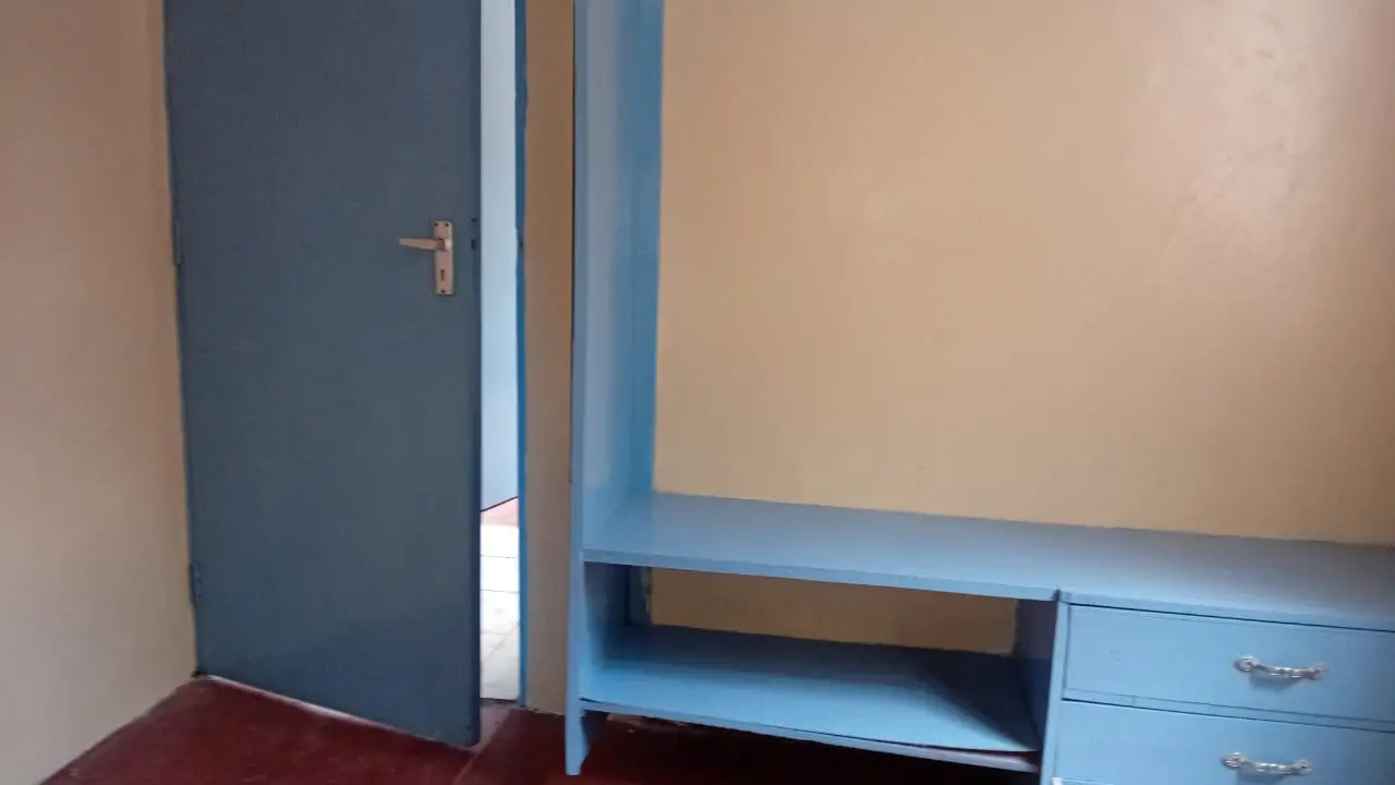 Bedroom with blue door, shelving unit, and red floor