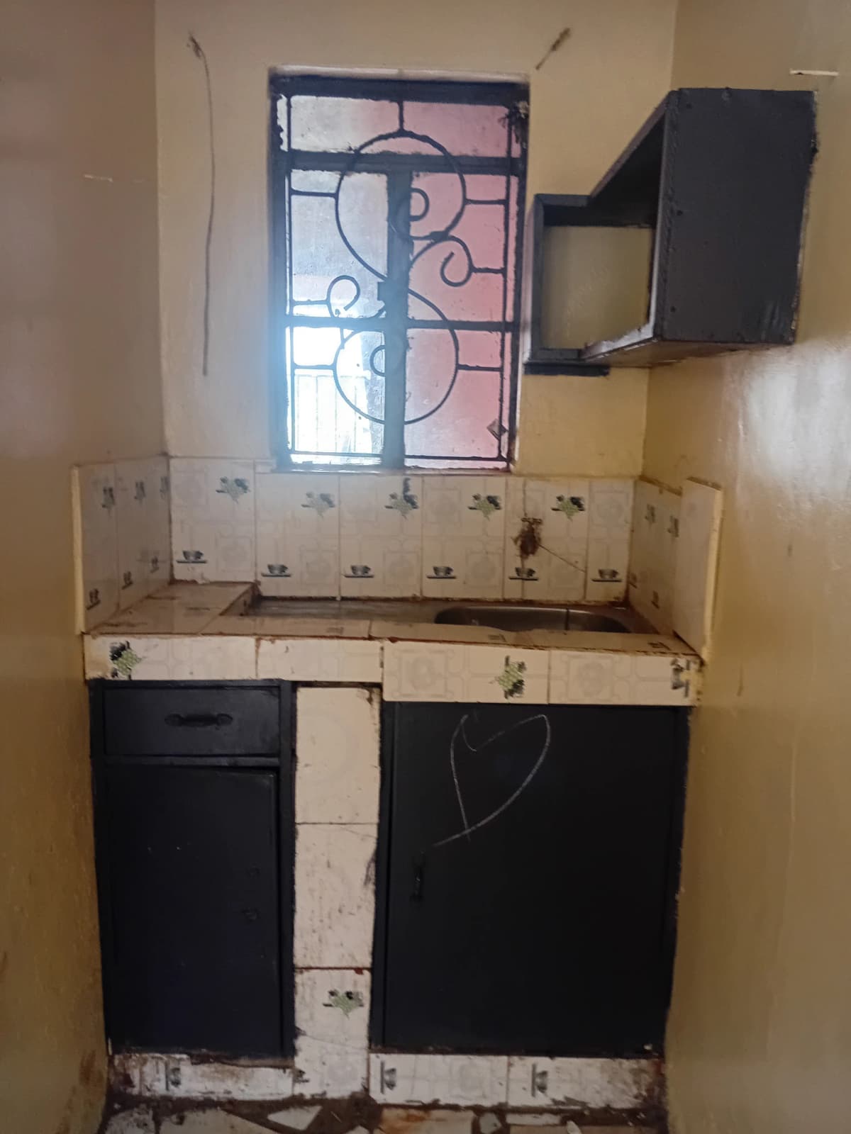 Compact kitchen with black cabinetry and decorative window