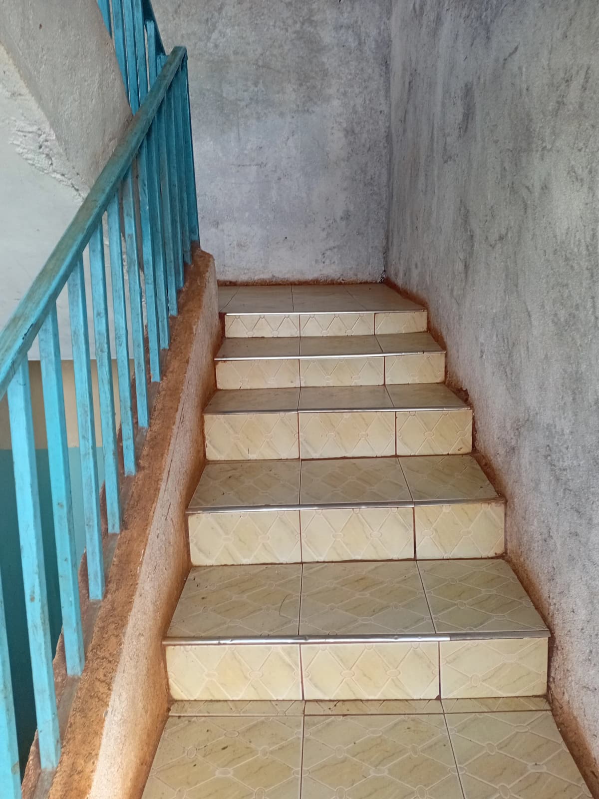 Interior staircase with blue railing and tile steps