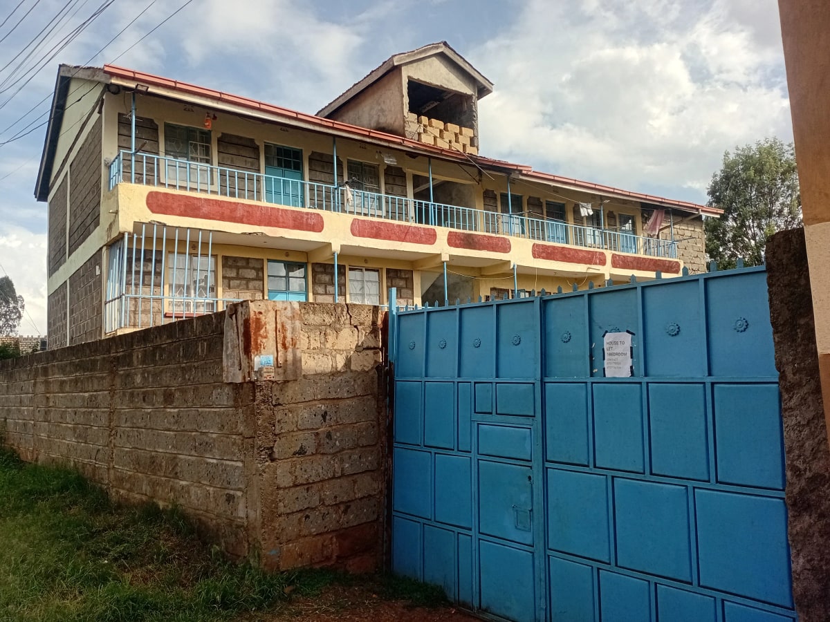 Multi-story residential building with blue perimeter gate