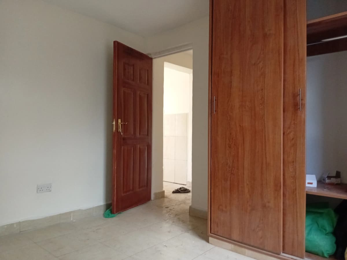 Unfurnished bedroom with wooden wardrobe and open door