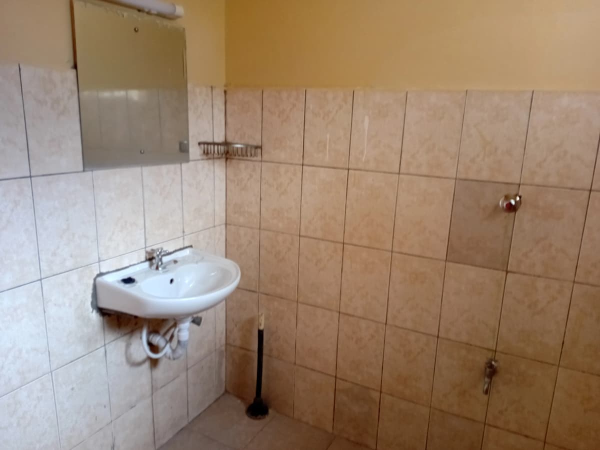 Basic bathroom with wall-mounted sink and tiled walls