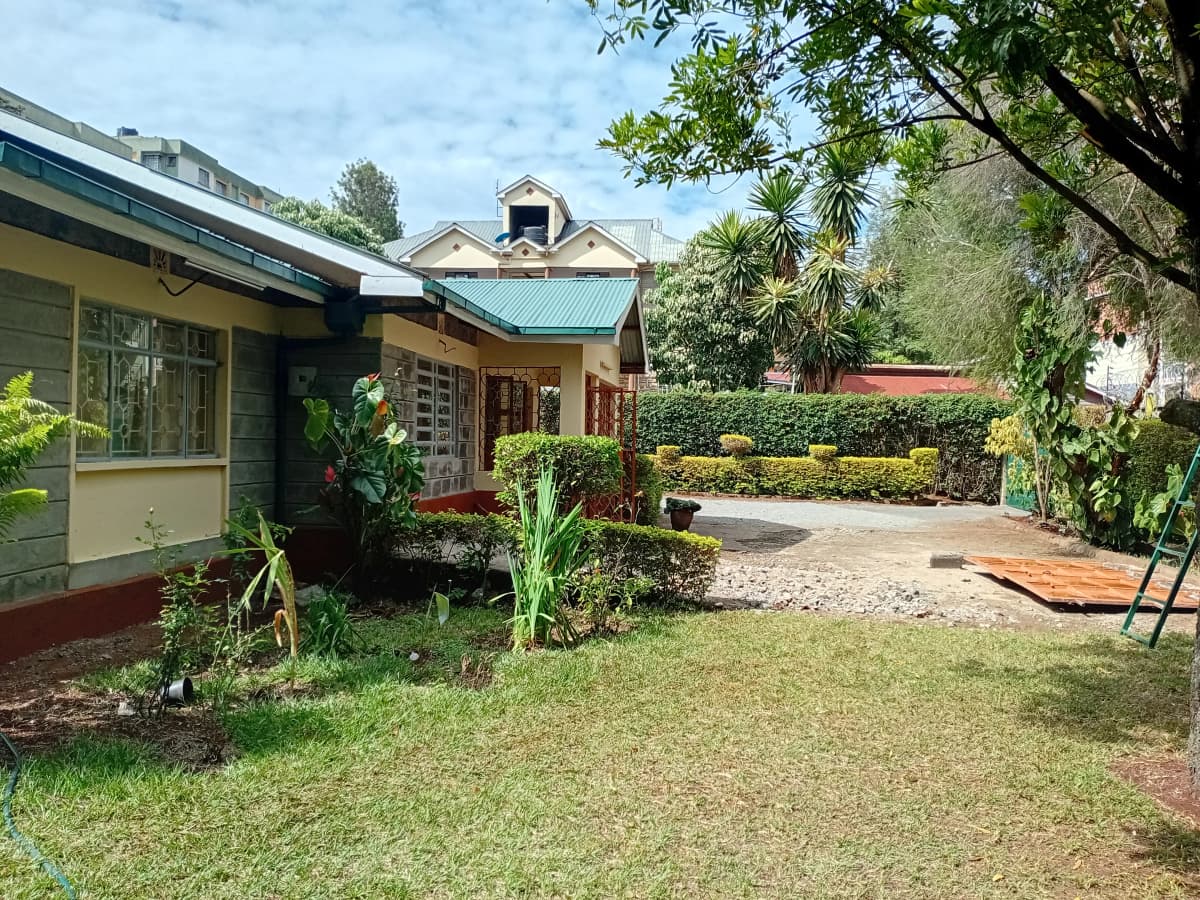 Spacious compound garden with manicured lawn and mature trees