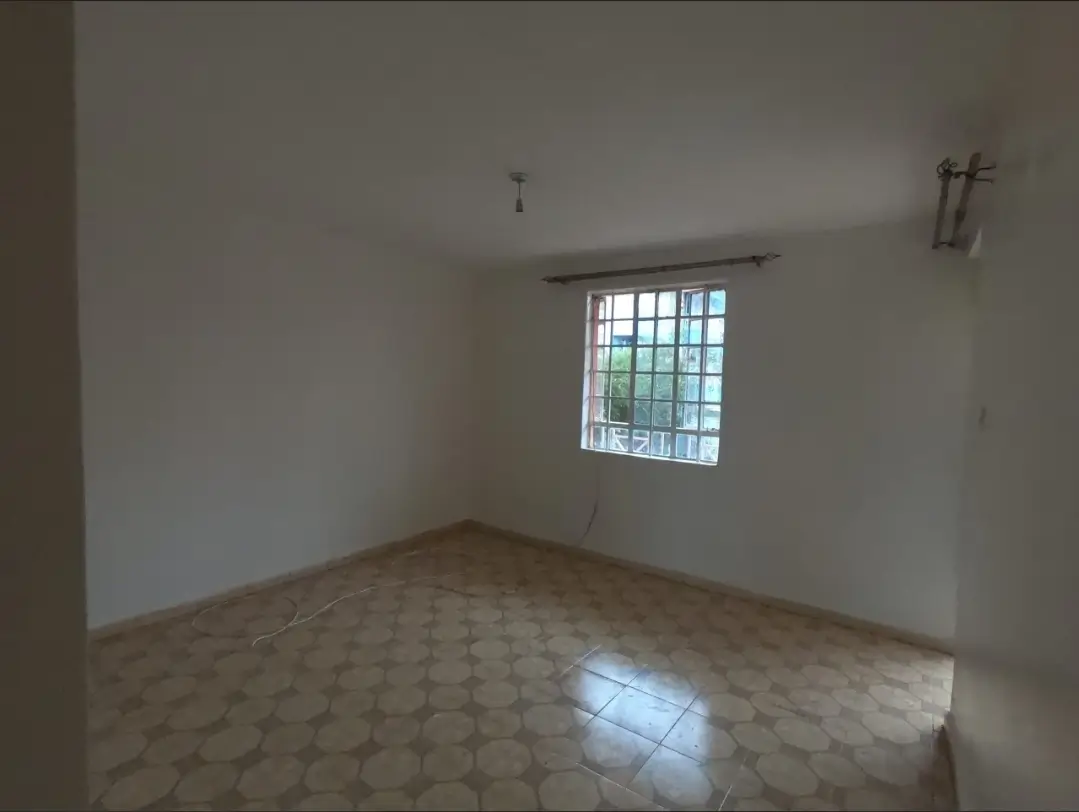 Empty bedroom with tiled floor and barred window