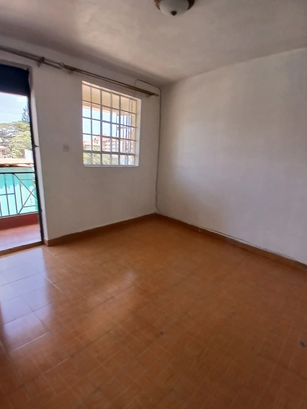 Spacious bedroom with terracotta floors and balcony access
