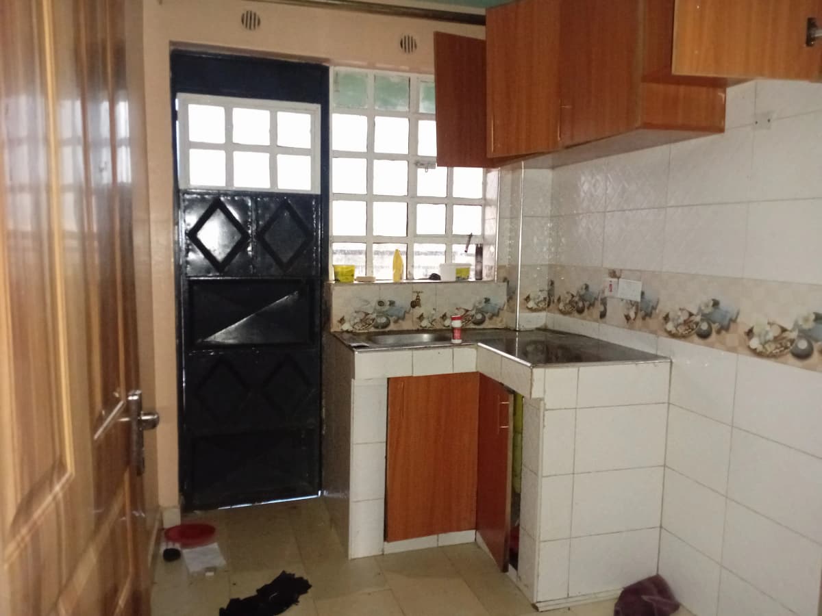 Compact kitchen with white tiles, wooden cabinets, black door