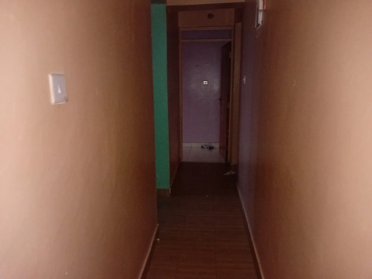 Narrow hallway with peach walls and dark flooring