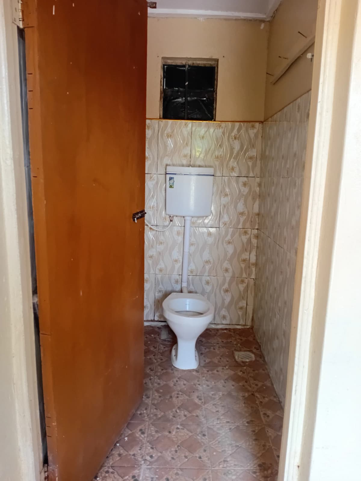 Compact toilet room with ceramic tiles and wall-mounted cistern