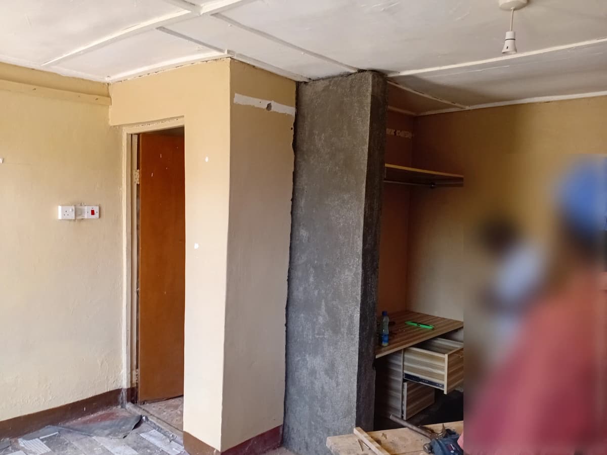 Unfurnished bedroom with concrete pillar and brown wooden door