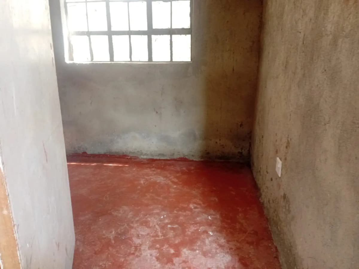 Unfurnished bedroom with red concrete floor and barred window