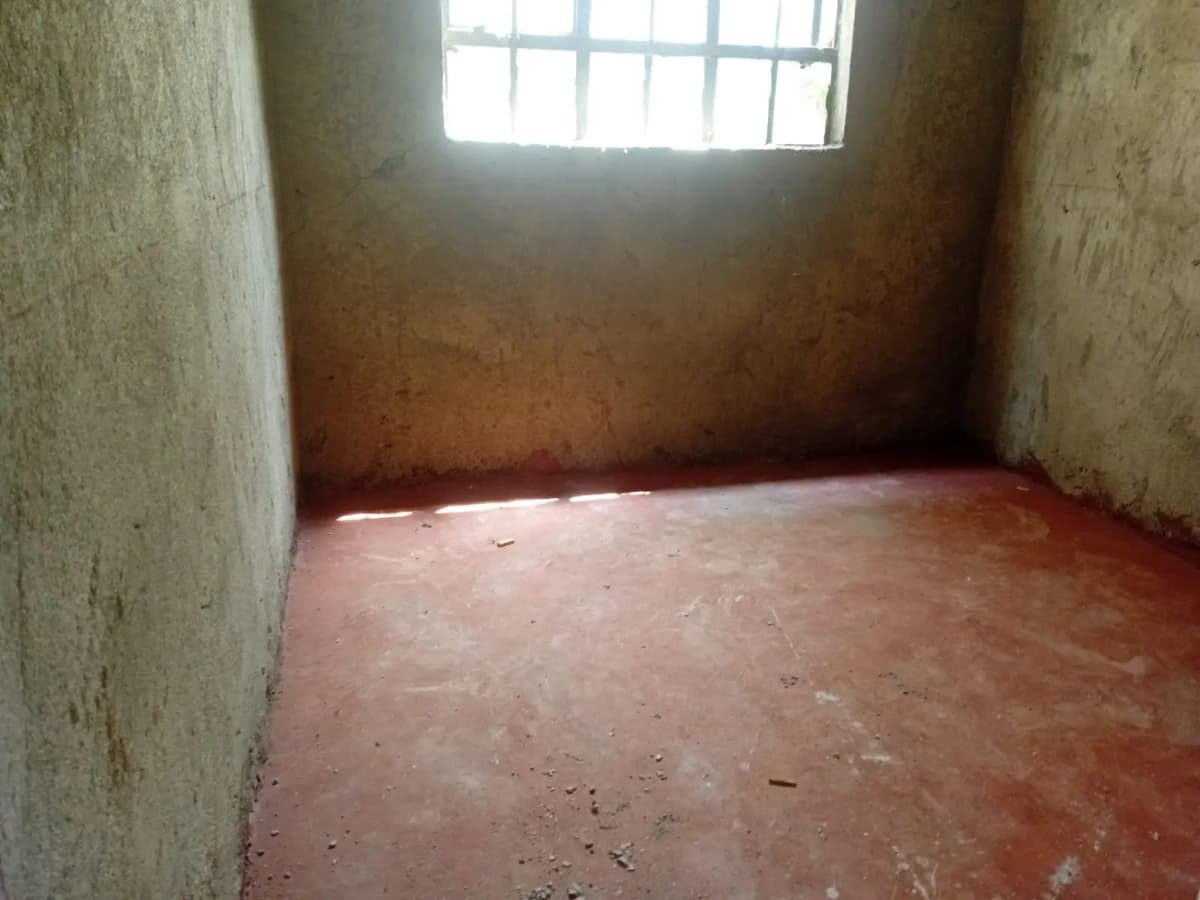 Empty room with terracotta floor and barred window