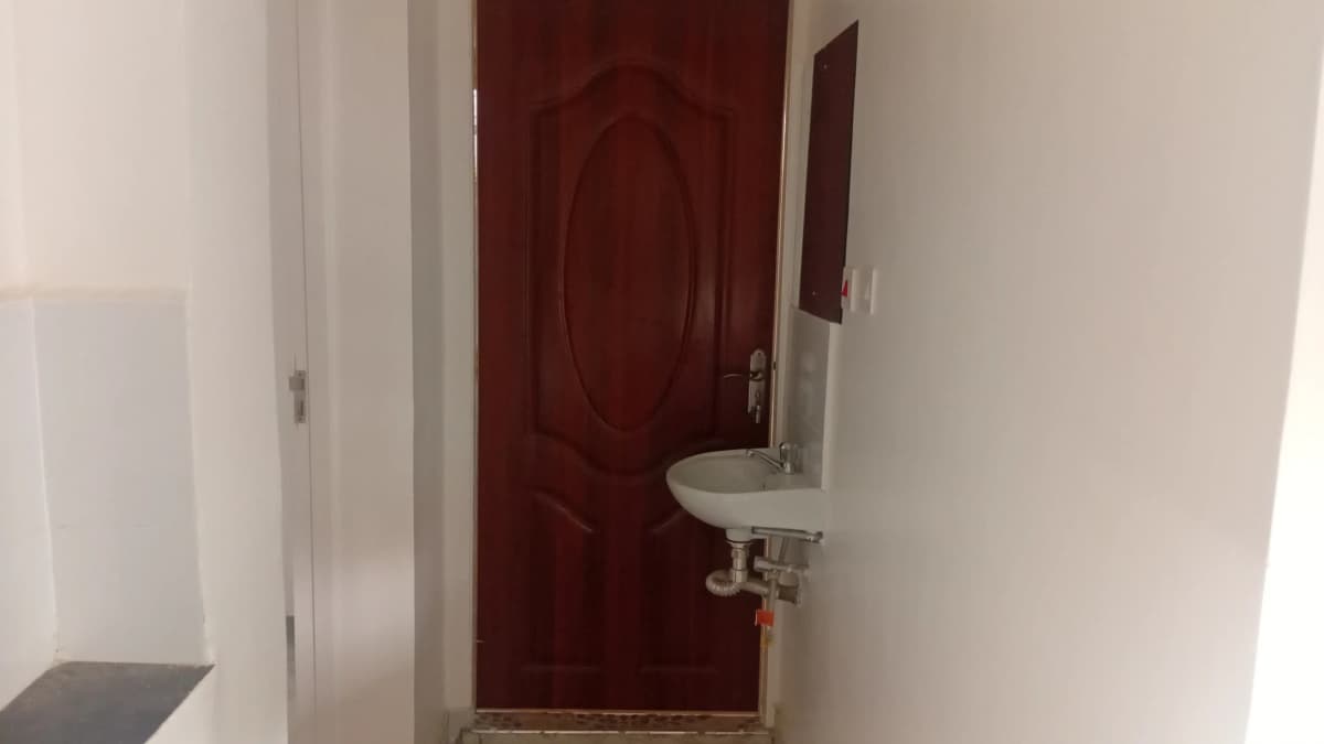 Compact bathroom with wall-mounted sink and burgundy door