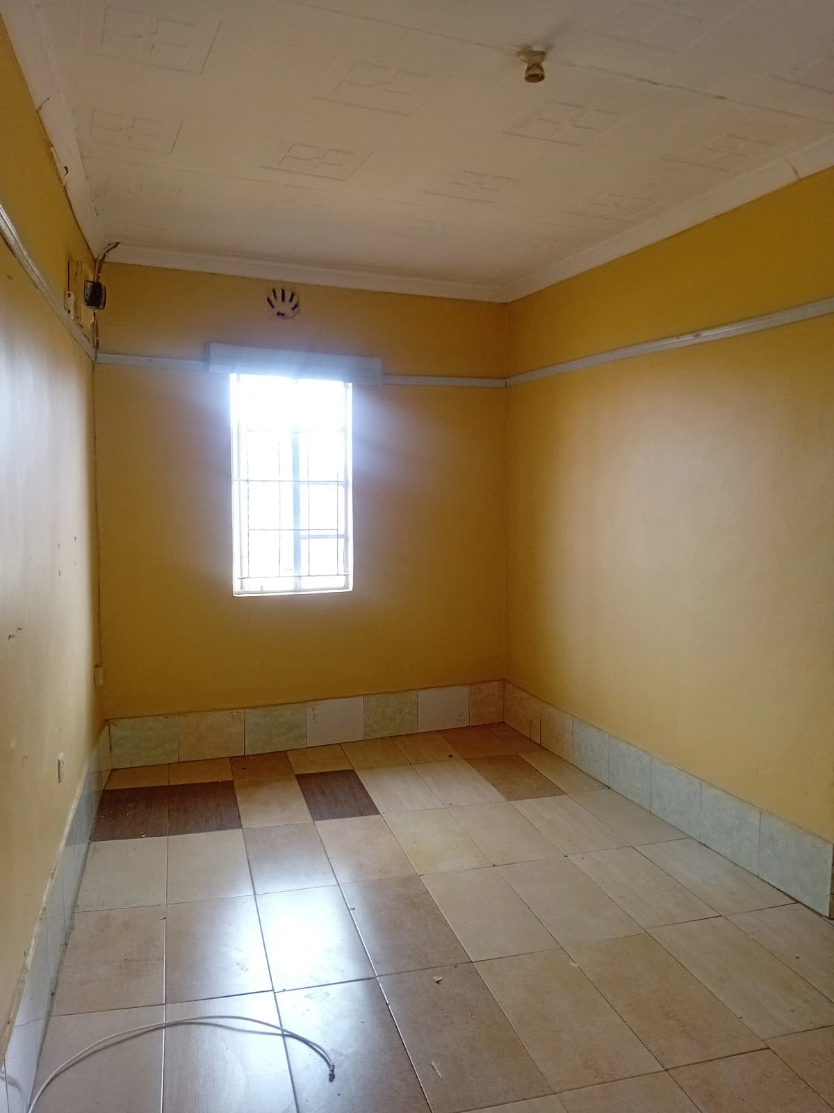 Empty bedroom with yellow walls and tiled flooring