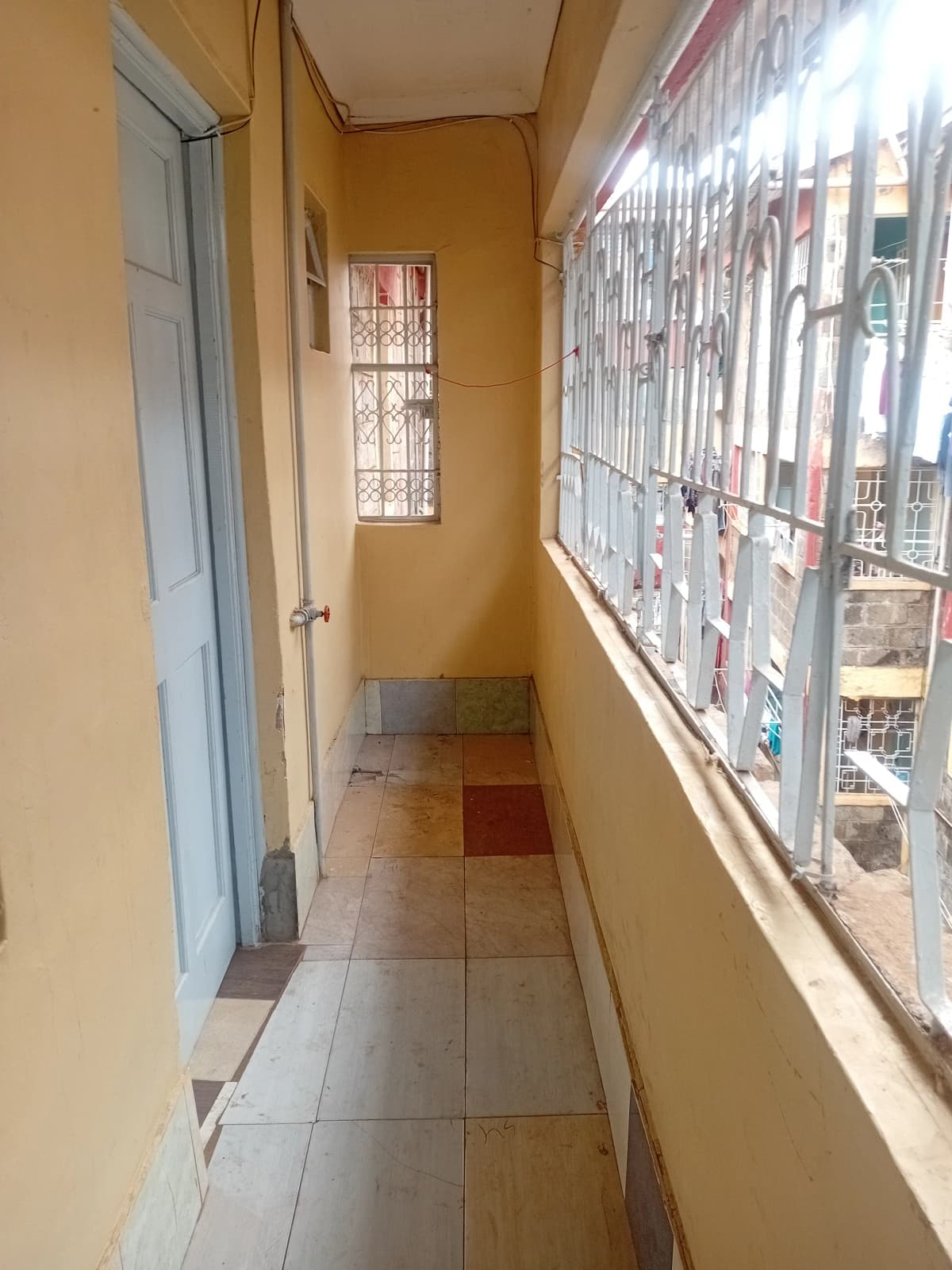 Narrow enclosed balcony with yellow walls and barred windows