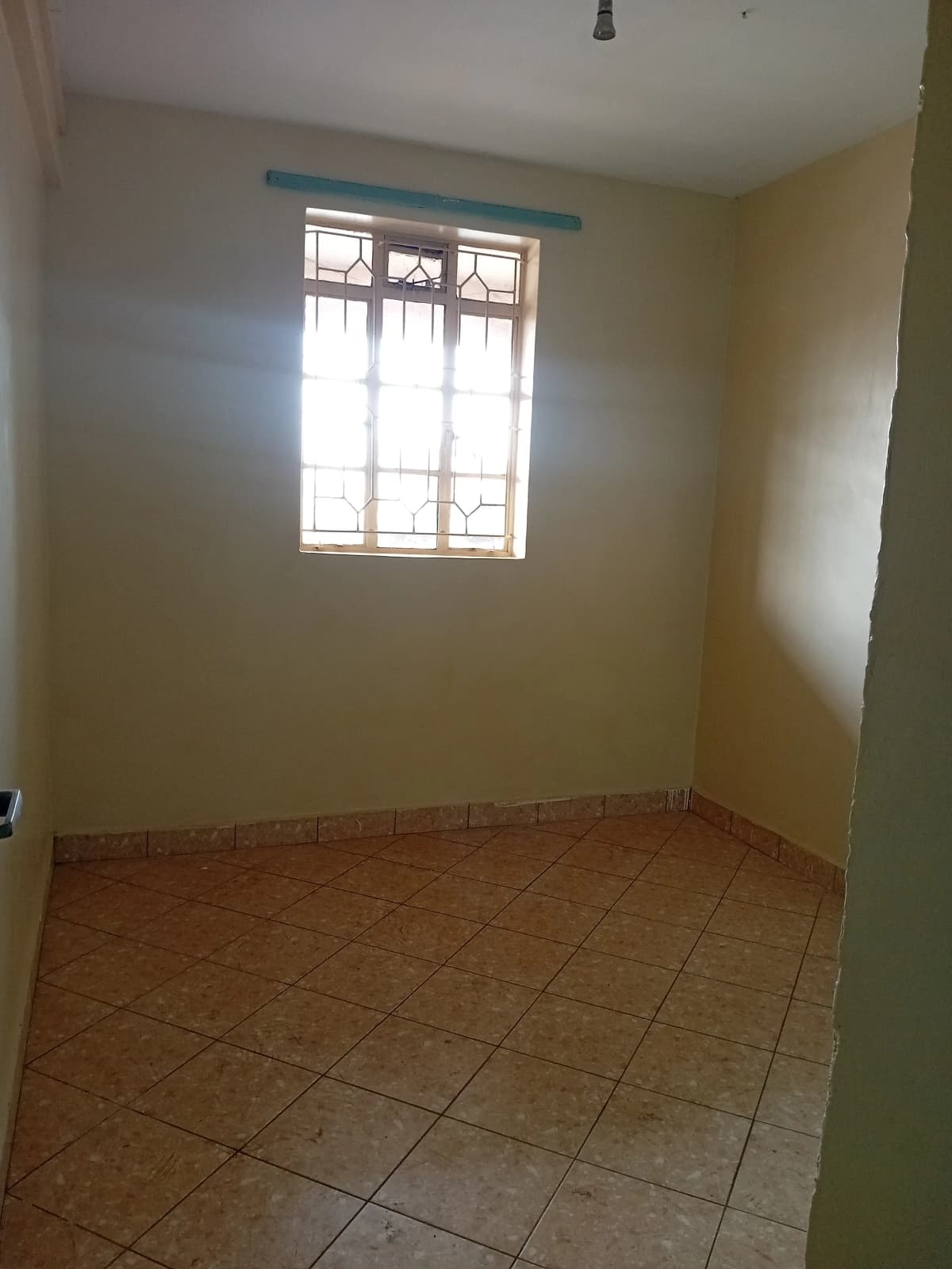 Bright bedroom with terracotta tiles and barred window